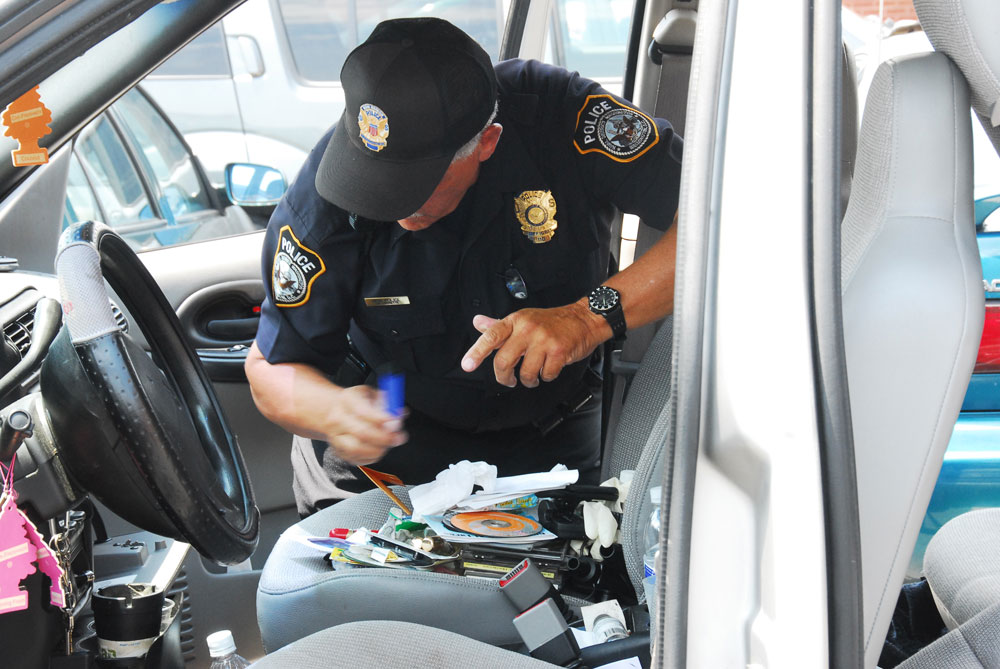 policeman searching for drugs in a car